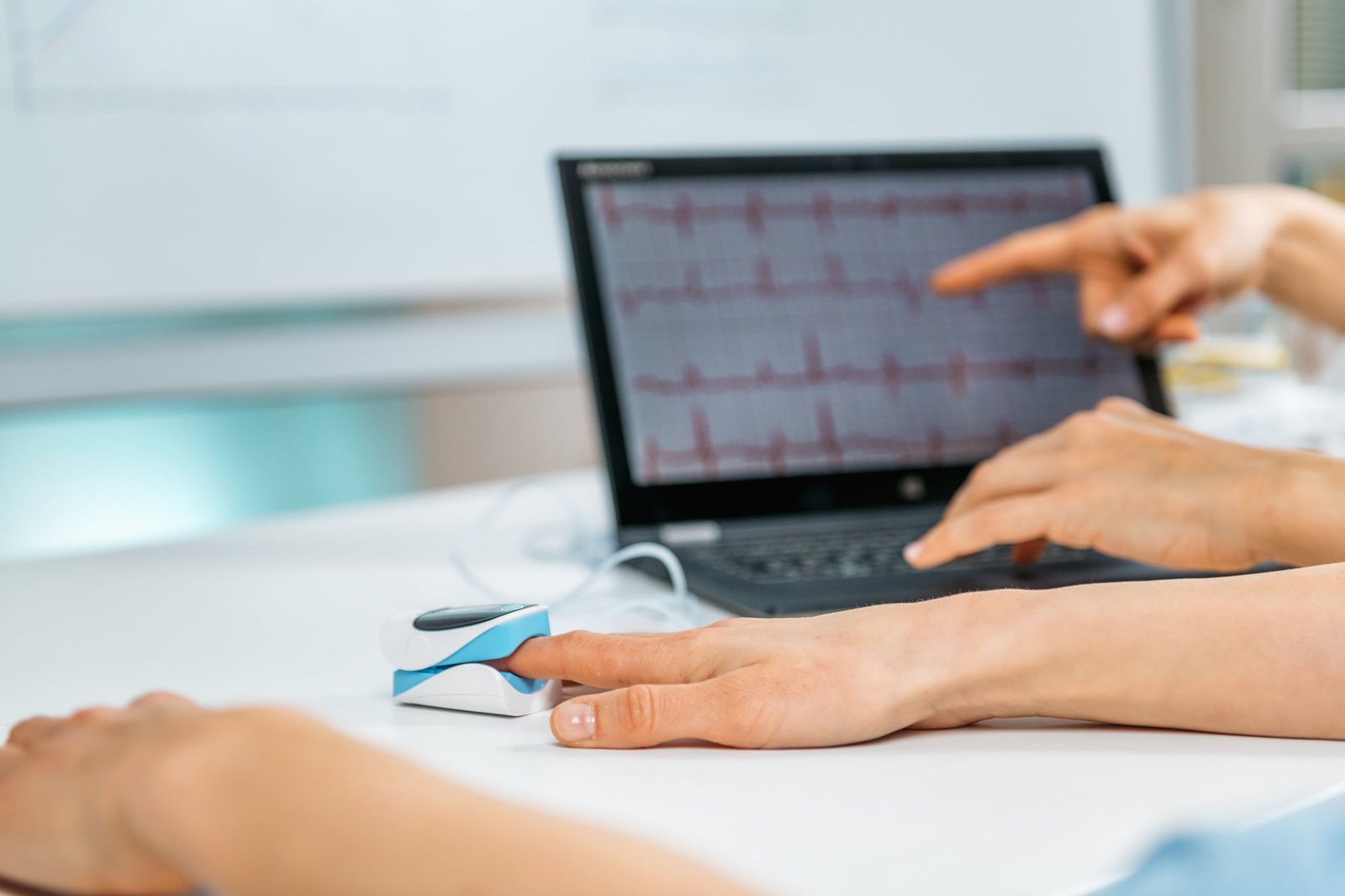 A clinician pointing at a heart rate variability trace on a laptop during a biofeedback session