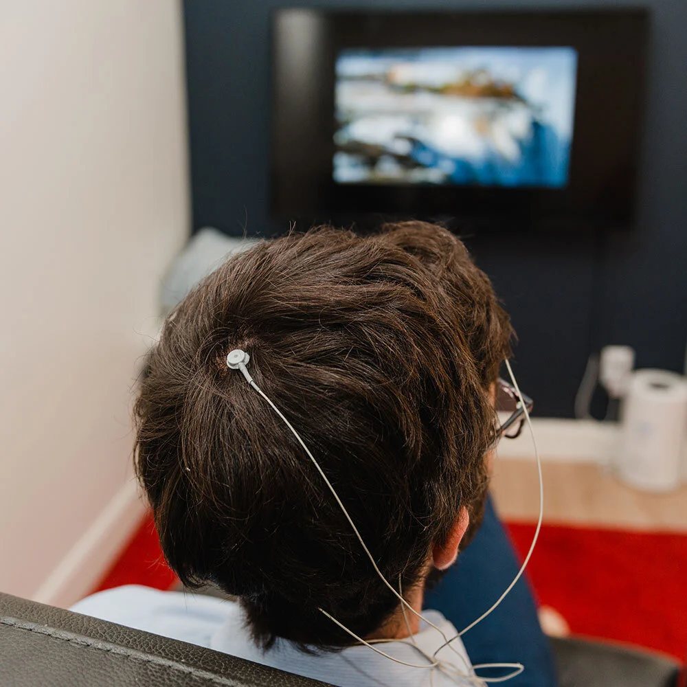 A person seen from behind training with neurofeedback in front of a screen